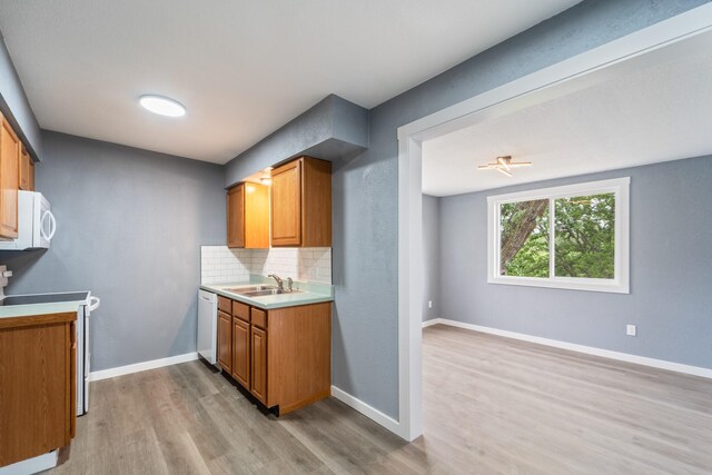 208 Van Buren Dr, Van Meter, IA 50261 - kitchen with white appliances, light wood-style floors, a sink, tasteful backsplash, and light countertops