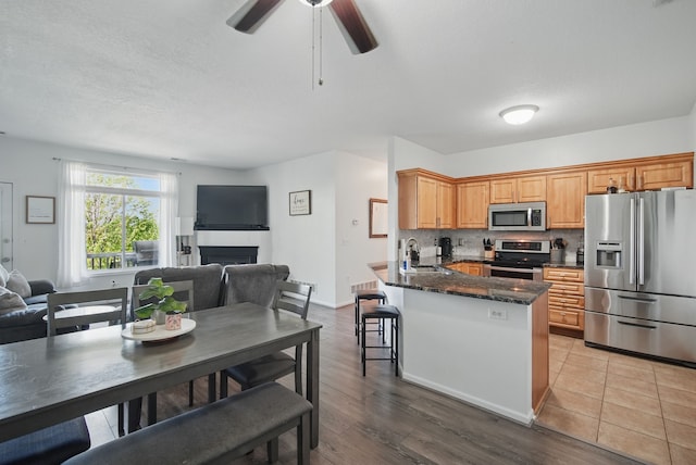 545 Maggie Ln, Altoona, IA 50009 - kitchen with appliances with stainless steel finishes, open floor plan, a peninsula, a sink, and a fireplace