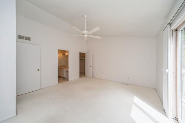 unfurnished bedroom featuring light carpet, connected bathroom, vaulted ceiling, and a ceiling fan