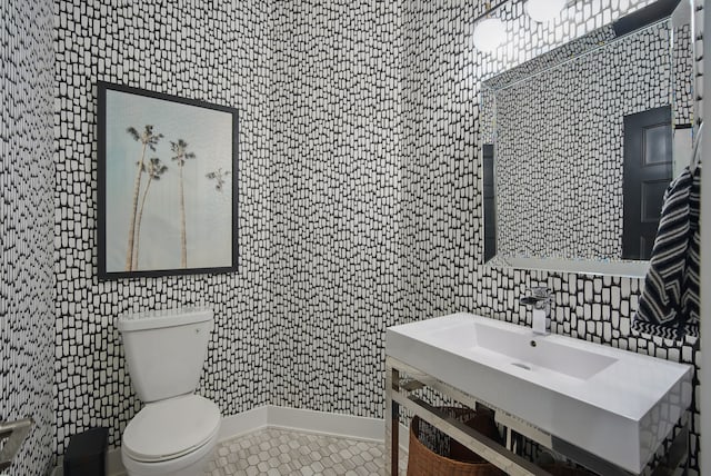16202 Brookview Dr, Urbandale, IA 50323 - bathroom featuring toilet, baseboards, tile walls, a sink, and tile patterned floors