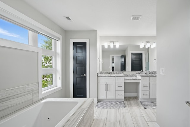 16202 Brookview Dr, Urbandale, IA 50323 - bathroom with healthy amount of natural light, a jetted tub, two vanities, and baseboards