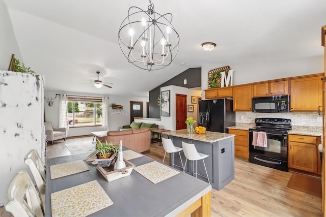 2009 NW Boulder Ridge Ln, Ankeny, IA 50023 - dining room featuring vaulted ceiling, light wood-type flooring, ceiling fan, and a chandelier