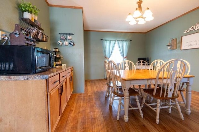 2002 12th St, Eldora, IA 50627 - dining space with crown molding, light wood-style flooring, and a chandelier