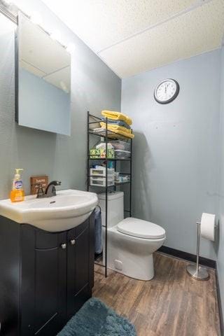 2002 12th St, Eldora, IA 50627 - half bath featuring wood finished floors, toilet, and vanity