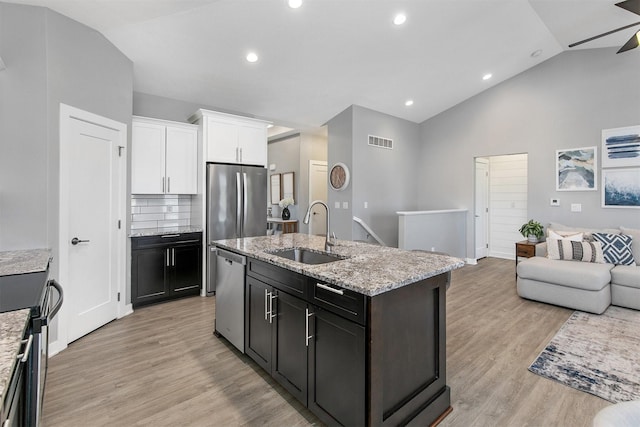 1350 97th St, West Des Moines, IA 50266 - kitchen featuring a sink, stainless steel appliances, white cabinetry, open floor plan, and a center island with sink