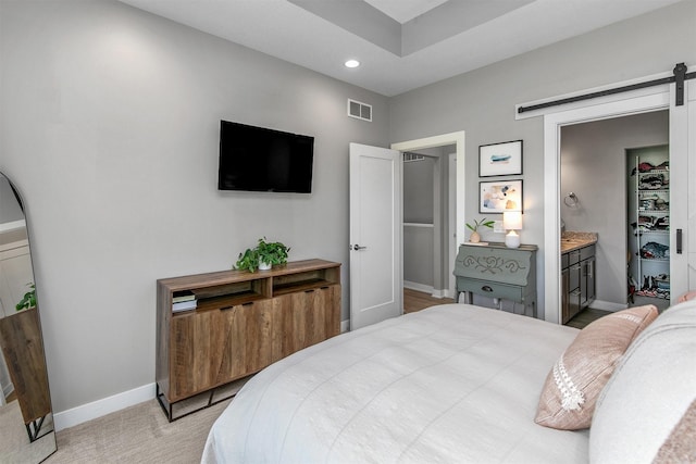 1350 97th St, West Des Moines, IA 50266 - bedroom featuring a barn door, baseboards, recessed lighting, ensuite bath, and light carpet