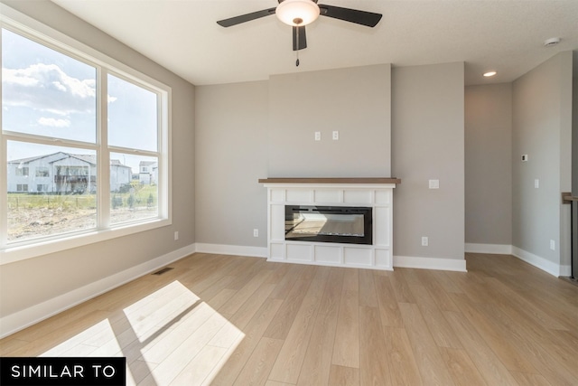 4120 NE 5th St, Ankeny, IA 50021 - unfurnished living room featuring ceiling fan, light wood-style flooring, plenty of natural light, a glass covered fireplace, and recessed lighting