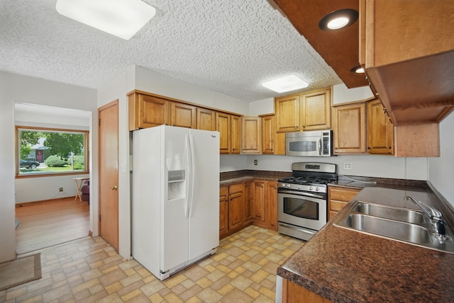4147 E 7th St, Des Moines, IA 50313 - kitchen featuring stainless steel appliances, a sink, dark countertops, brown cabinets, and recessed lighting