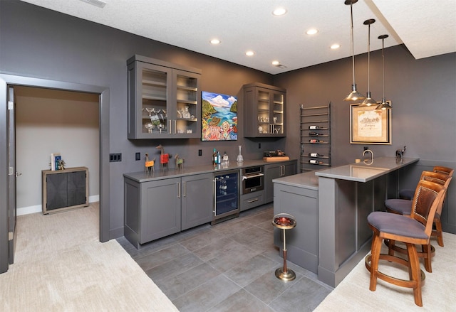 8115 Cobblestone Ct, Urbandale, IA 50322 - indoor wet bar featuring beverage cooler, recessed lighting, stainless steel oven, pendant lighting, and light tile patterned floors