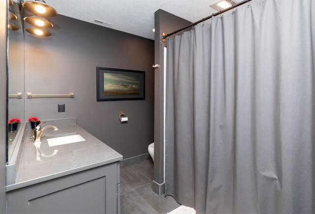8115 Cobblestone Ct, Urbandale, IA 50322 - bathroom featuring toilet, vanity, a textured ceiling, and tile patterned floors