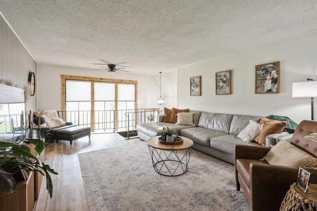 306 E Buchanan St, Baxter, IA 50028 - living room featuring wood finished floors, plenty of natural light, a textured ceiling, a ceiling fan, and wood walls