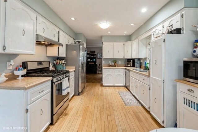 4511 66th St, Urbandale, IA 50322 - kitchen with appliances with stainless steel finishes, under cabinet range hood, a sink, white cabinetry, and light countertops