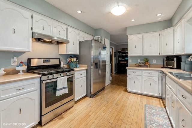 4511 66th St, Urbandale, IA 50322 - kitchen with appliances with stainless steel finishes, under cabinet range hood, white cabinets, light countertops, and light wood-type flooring