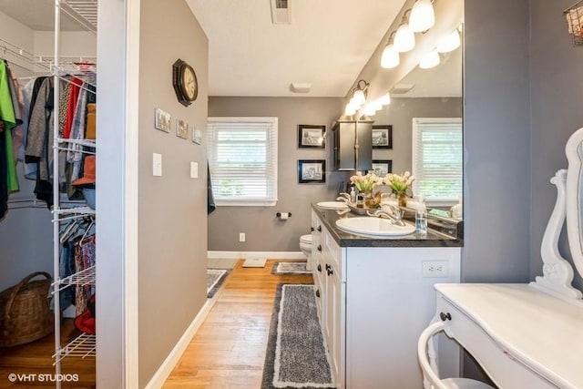 4511 66th St, Urbandale, IA 50322 - full bathroom featuring wood finished floors, baseboards, vanity, toilet, and a spacious closet