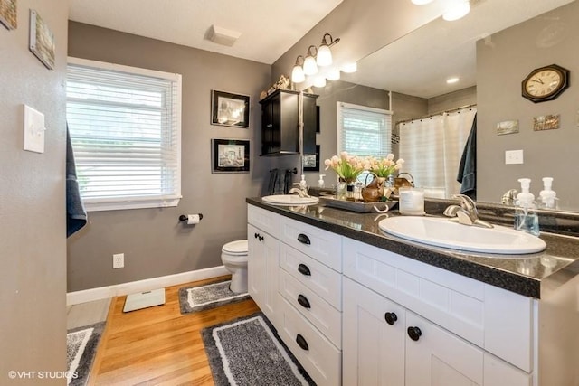 4511 66th St, Urbandale, IA 50322 - full bathroom with toilet, wood finished floors, double vanity, a shower with shower curtain, and baseboards