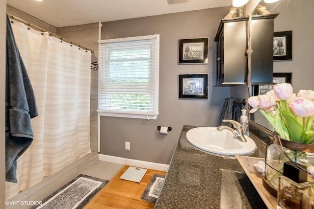 4511 66th St, Urbandale, IA 50322 - bathroom featuring wood finished floors, a shower with curtain, vanity, and baseboards