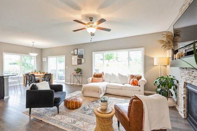 1085 Juniper Dr, Carlisle, IA 50047 - living room featuring a ceiling fan, a stone fireplace, baseboards, and dark wood finished floors