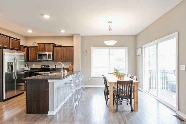 1085 Juniper Dr, Carlisle, IA 50047 - kitchen featuring appliances with stainless steel finishes, a sink, dark stone counters, baseboards, and light wood-style floors