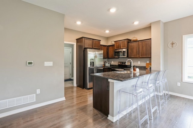 1085 Juniper Dr, Carlisle, IA 50047 - kitchen featuring appliances with stainless steel finishes, a sink, a peninsula, dark stone countertops, and baseboards