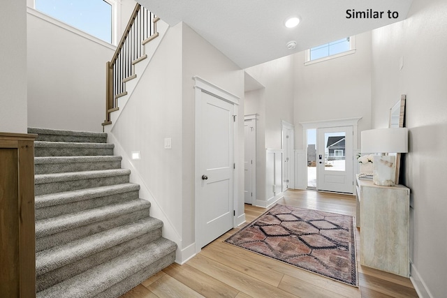 2228 Green Leaf Cir, Norwalk, IA 50211 - entryway with wood finished floors, stairway, a towering ceiling, and baseboards