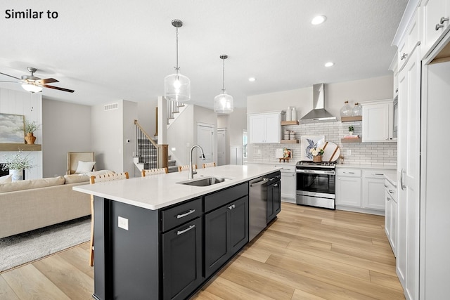 2228 Green Leaf Cir, Norwalk, IA 50211 - kitchen with appliances with stainless steel finishes, wall chimney range hood, white cabinetry, open floor plan, and recessed lighting