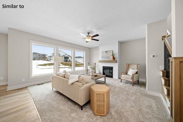 2228 Green Leaf Cir, Norwalk, IA 50211 - living area featuring ceiling fan, a large fireplace, a textured ceiling, light wood-type flooring, and baseboards