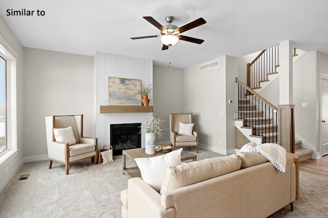 2228 Green Leaf Cir, Norwalk, IA 50211 - carpeted living area with stairs, a fireplace, ceiling fan, and baseboards