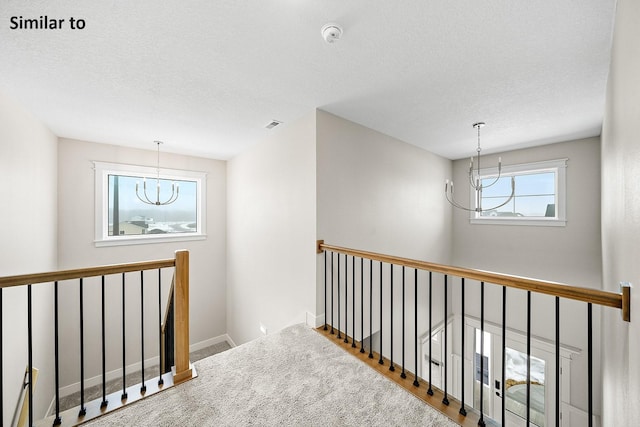2228 Green Leaf Cir, Norwalk, IA 50211 - hall featuring a chandelier, an upstairs landing, a textured ceiling, and baseboards