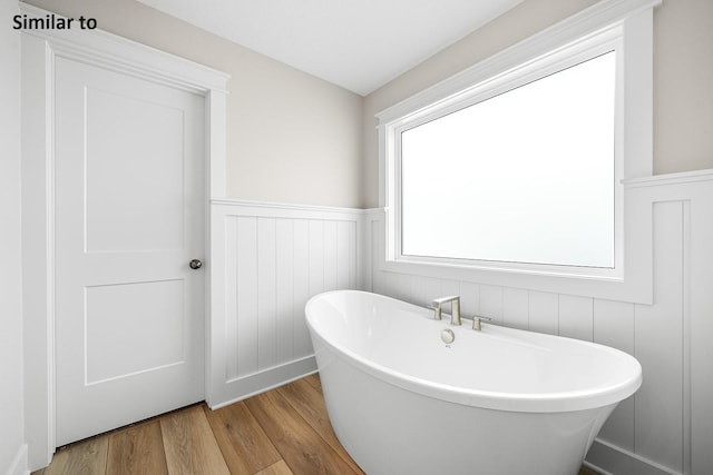 2228 Green Leaf Cir, Norwalk, IA 50211 - bathroom featuring wood finished floors, wainscoting, and a freestanding tub