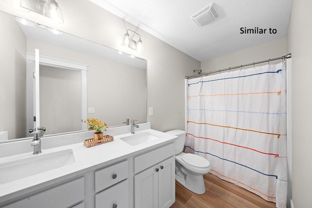 2228 Green Leaf Cir, Norwalk, IA 50211 - full bathroom featuring double vanity, wood finished floors, curtained shower, and a textured ceiling