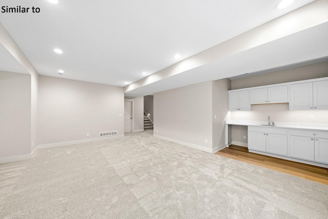 2228 Green Leaf Cir, Norwalk, IA 50211 - unfurnished living room featuring baseboards, light carpet, stairs, recessed lighting, and a sink
