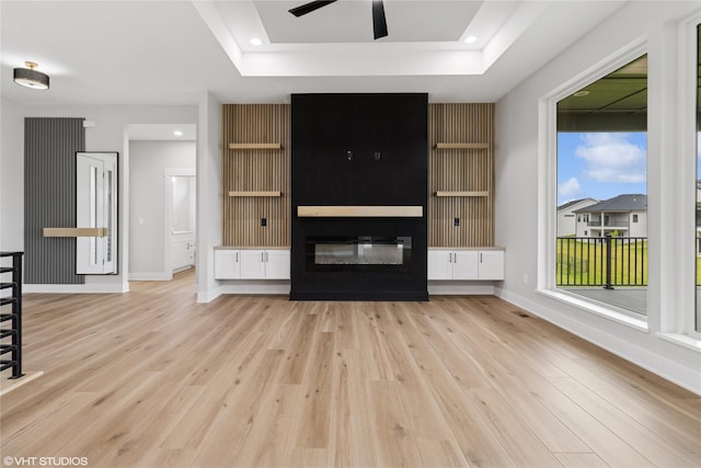 17400 Springbrook Trl, Urbandale, IA 50111 - unfurnished living room featuring light wood-style flooring, a ceiling fan, a raised ceiling, baseboards, and a fireplace