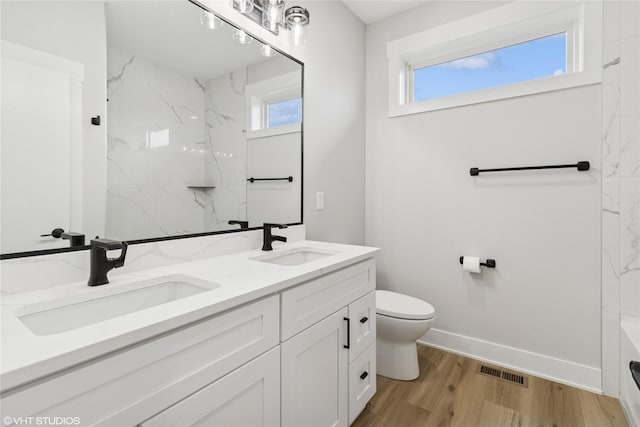 17400 Springbrook Trl, Urbandale, IA 50111 - bathroom with toilet, wood finished floors, double vanity, baseboards, and a bath