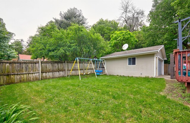 1236 63rd St, Windsor Heights, IA 50324 - view of yard featuring a playground, an outbuilding, view of wooded area, and a detached garage