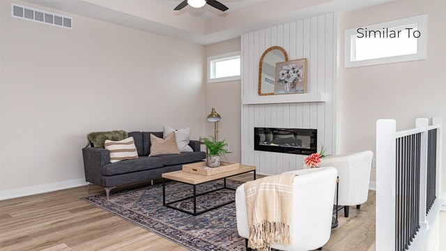 610 NW Georgetown Dr, Waukee, IA 50263 - living area featuring a ceiling fan, wood finished floors, a large fireplace, and baseboards