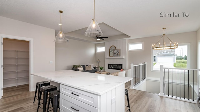 610 NW Georgetown Dr, Waukee, IA 50263 - kitchen featuring light wood-style floors, a kitchen bar, white cabinetry, a kitchen island, and a chandelier