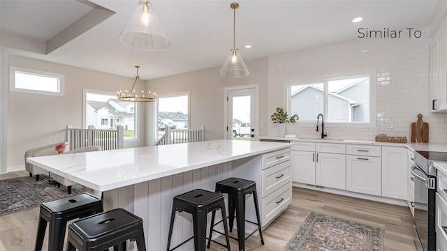 610 NW Georgetown Dr, Waukee, IA 50263 - kitchen with a sink, a breakfast bar, light wood-type flooring, stainless steel electric range, and recessed lighting