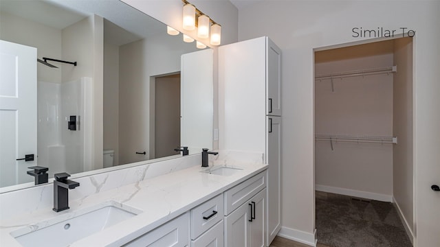 610 NW Georgetown Dr, Waukee, IA 50263 - full bath featuring double vanity, baseboards, a walk in closet, and toilet