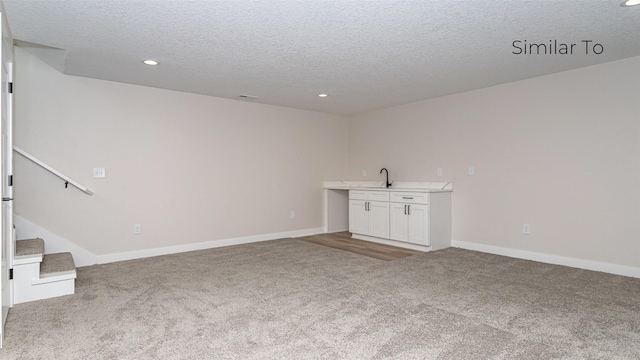 610 NW Georgetown Dr, Waukee, IA 50263 - unfurnished living room featuring light colored carpet, a textured ceiling, recessed lighting, stairs, and baseboards