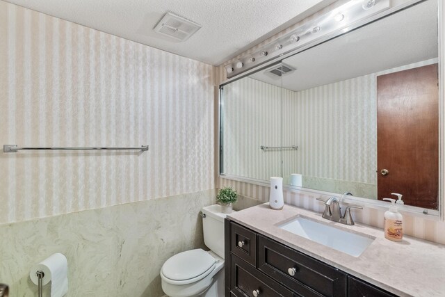 4633 Lockner Dr Unit 3, Urbandale, IA 50322 - bathroom with wallpapered walls, toilet, a textured ceiling, and vanity