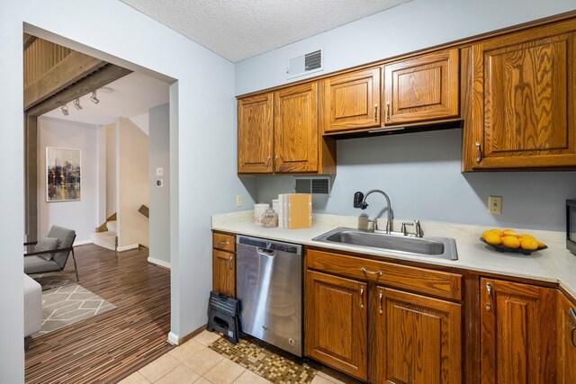 4633 Lockner Dr Unit 3, Urbandale, IA 50322 - kitchen featuring dishwasher, a sink, light countertops, brown cabinets, and a textured ceiling