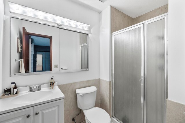4633 Lockner Dr Unit 3, Urbandale, IA 50322 - full bath with a shower stall, toilet, a wainscoted wall, tile walls, and vanity