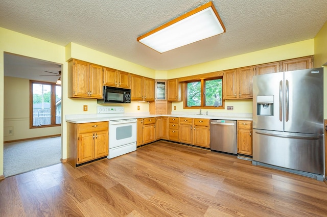 4521 77th St, Urbandale, IA 50322 - kitchen featuring appliances with stainless steel finishes, a sink, light wood finished floors, light countertops, and a textured ceiling