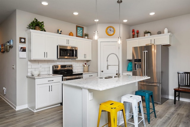 1917 Southbridge Dr, Adel, IA 50003 - kitchen with stainless steel appliances, light wood-type flooring, a breakfast bar, white cabinets, and recessed lighting