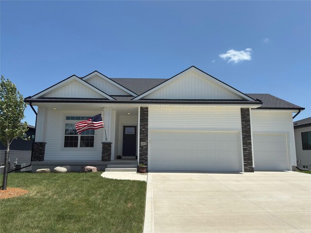 1917 Southbridge Dr, Adel, IA 50003 - view of front of home featuring a garage, concrete driveway, a front lawn, stone siding, and roof with shingles