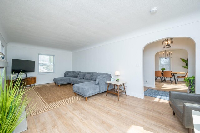 211 Park Ave, Des Moines, IA 50315 - living area featuring arched walkways, a chandelier, light wood-style floors, and baseboards