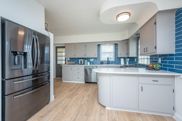 211 Park Ave, Des Moines, IA 50315 - kitchen with appliances with stainless steel finishes, gray cabinets, a peninsula, and light wood-style floors