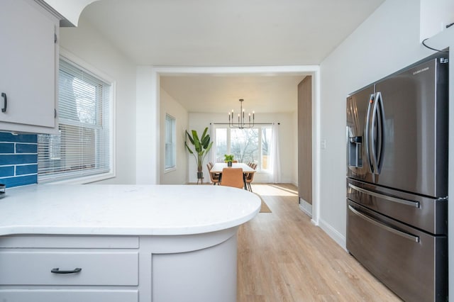 211 Park Ave, Des Moines, IA 50315 - kitchen with stainless steel fridge with ice dispenser, a chandelier, light wood-style flooring, baseboards, and a peninsula