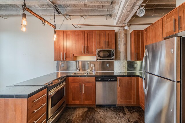 112 11th St Unit 506, Des Moines, IA 50309 - kitchen with stainless steel appliances, a sink, a peninsula, brown cabinets, and pendant lighting