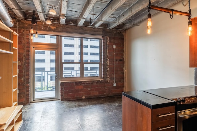 112 11th St Unit 506, Des Moines, IA 50309 - kitchen featuring tile counters, concrete floors, stainless steel range with electric stovetop, and brick wall